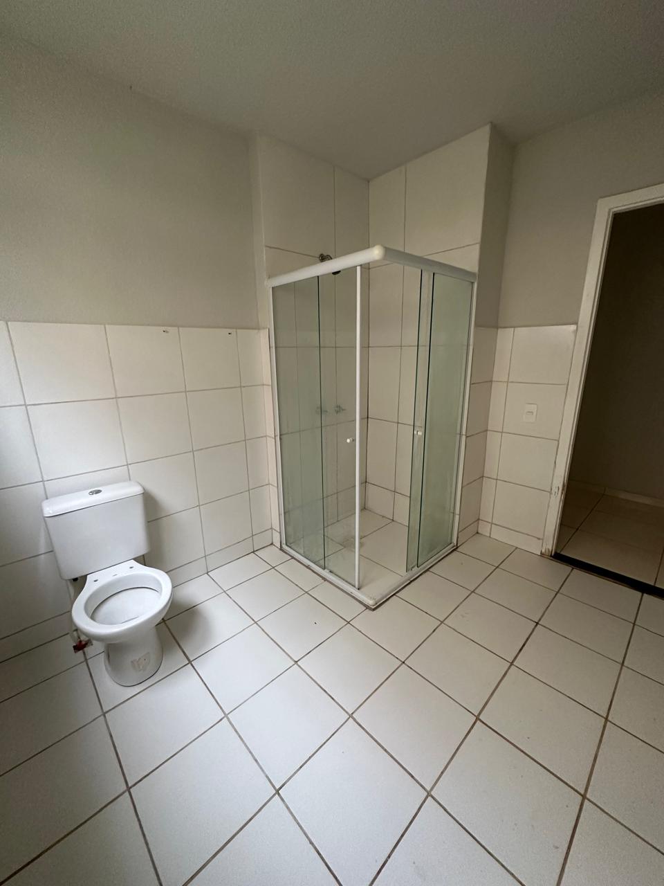 Banheiro com box de vidro e revestimentos claros